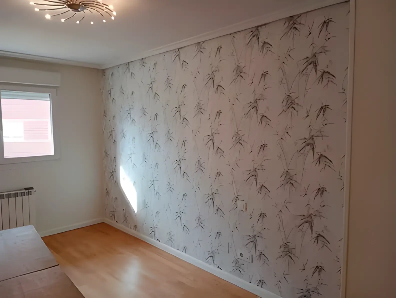 Los Pintores en Córdoba colocando papel pintado en pared de acento de habitación luminosa